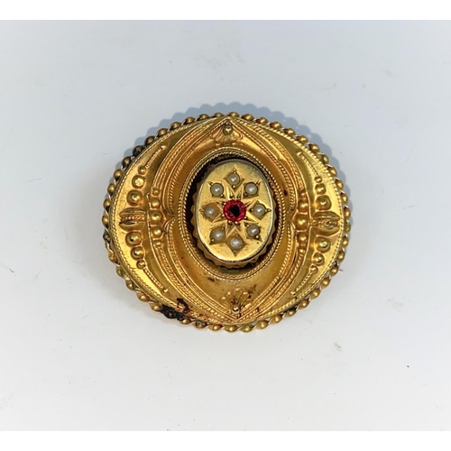 413 - A Victorian oval filigree brooch set ruby and seed pearl, in yellow metal stamped '9c', 5.5 gm