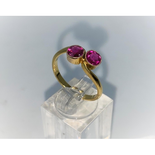 378 - A yellow metal cross over style dress ring set with 2 ruby coloured stones, unmarked tests as 18 ct,... 