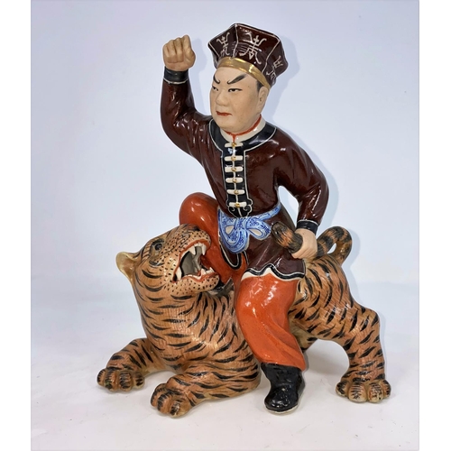 285 - A Chinese ceramic figure of man seated on a tiger holding its tail, unmarked, height 21.5cm