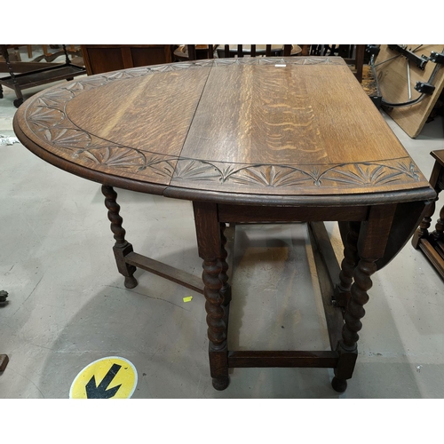 503 - An oak dining table with oval carved drop leaf top, on barley twist legs