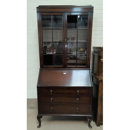 514 - A 1930's oak bureau/bookcase with twin glazed doors over fall front and 3 drawers, on cabriole legs ... 
