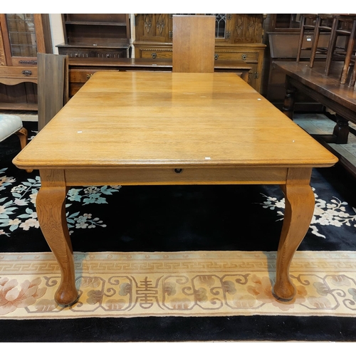 523 - A large late 19th / early 20th century rectangular golden oak wind out dining table on cabriole legs... 