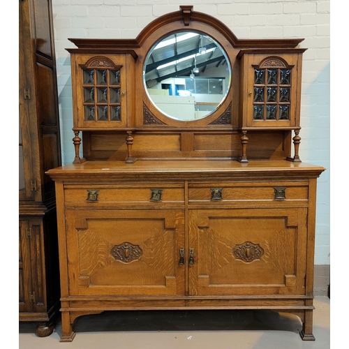 639 - A late Arts & Crafts golden oak sideboard of 2 cupboards with convex glass panels, and circular mirr... 