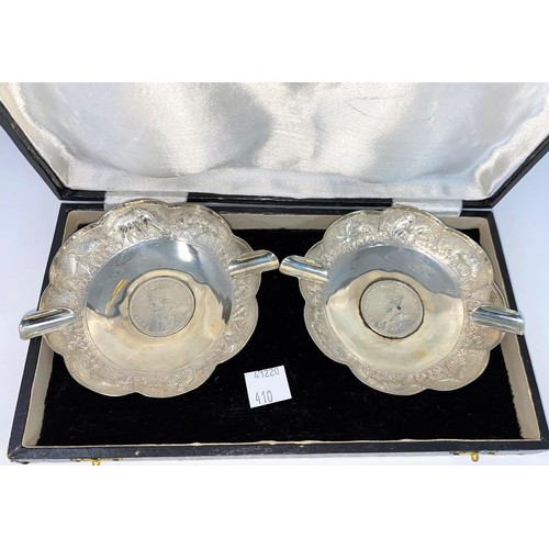 410 - A cased pair of Indian white metal ash trays with scalloped and embossed borders, each inset with Ge... 