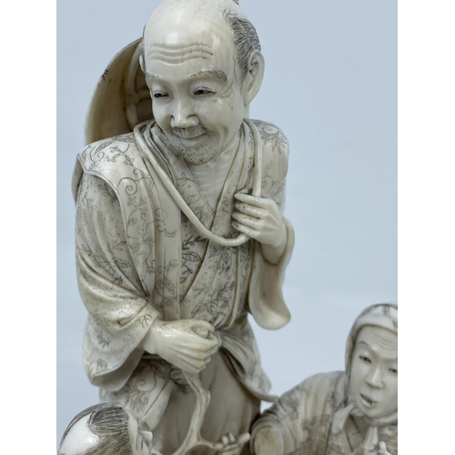 284A - A finely carved late 19th / early 20th century Japanese ivory family group of fisher folk, the man h... 