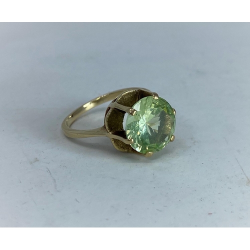 373 - A yellow metal dress ring  with citrine / peridot type stone in raised setting, tests as 9 ct, size ... 