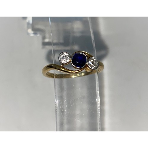 360A - A yellow metal three stone diamond and sapphire ring in crossover setting stamped 18ct 2.6gms