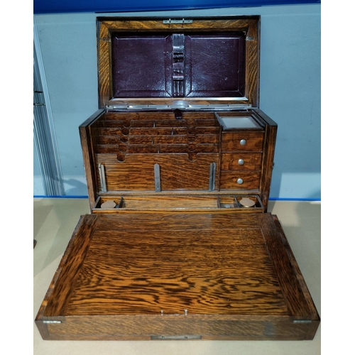 128 - An early 20th century oak stationery cabinet with out-folding writing slope, fitted interior with dr... 