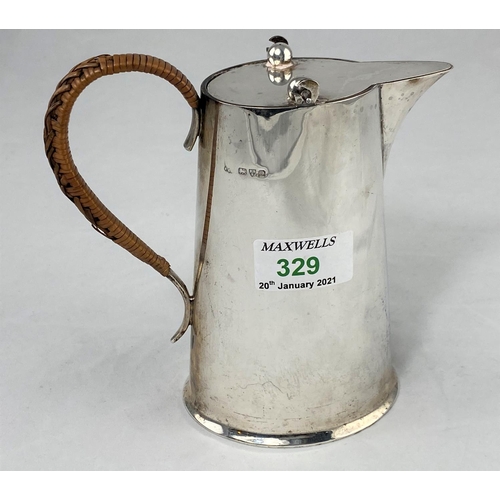 329 - A hot water jug of tapering oval form, with cane bound handle, Chester 1916, 9.5oz. (296gm)