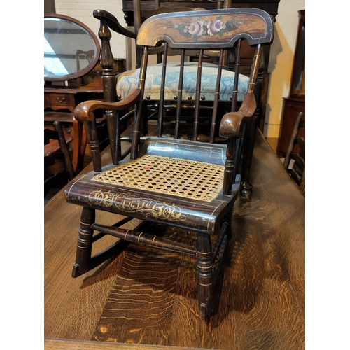 563 - A 19t century child's rocking armchair with stick back and cane seat, painted decoration