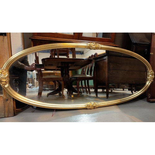 670 - A large wall mirror in gilt oval frame decorated with roses in relief, length 176 cm