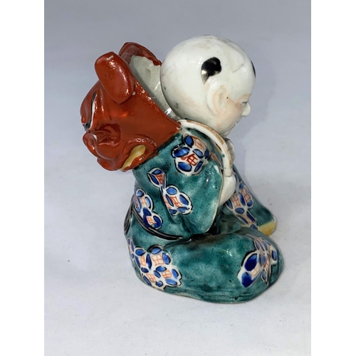 161 - A Chinese porcelain figure depicting a seated man in green robe with lion mask on his back, height 1... 