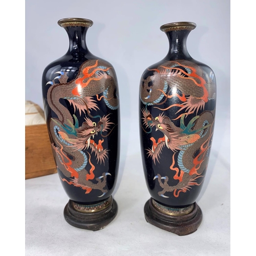 171 - A Japanese pair of cloisonné enamel vases decorated with dragons, turned hardwood bases, in original... 