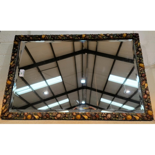 99 - A bevelled edge wall mirror in barbola type rectangular frame, decorated with painted fruit, 72 x 47... 