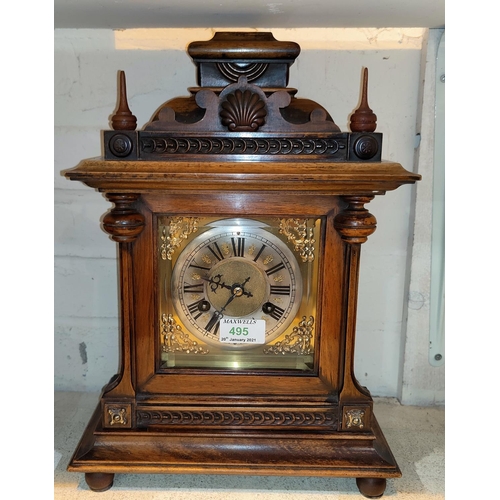 495 - An Edwardian mantel clock in stained walnut architectural case with turned finials, brass dial and s... 