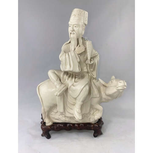159a - A Chinese blanc de chine group, man sat on cow, on wooden stand, full height 33cm (cow head a.f.)