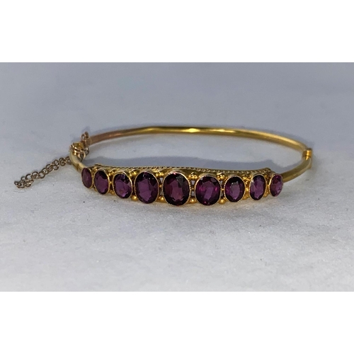 296 - An Edwardian 9 carat hallmarked gold hinged bracelet set 9 graduating oval amethysts, 5.1 gm (minor ... 
