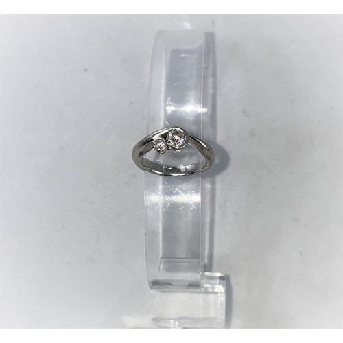300 - A white metal crossover ring set a large and a small diamond, stamped 'PT900', larger stone approx .... 