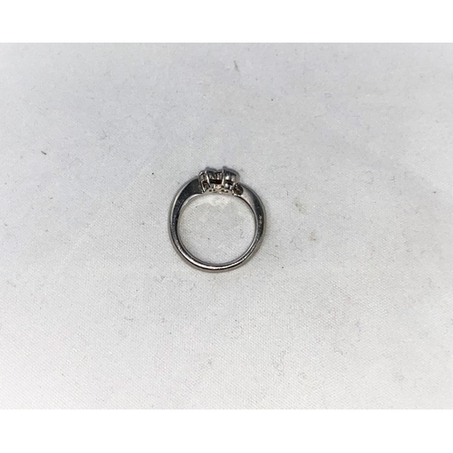 300 - A white metal crossover ring set a large and a small diamond, stamped 'PT900', larger stone approx .... 