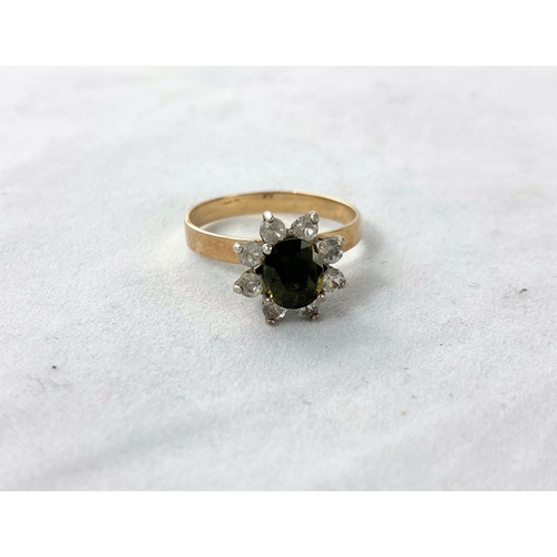 305 - A 1970's dress ring set green topaz surrounded by clear stones in flower head setting, stamped '9ct'... 