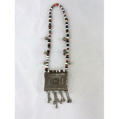 306 - A Mid/Far Eastern white metal large pendant of filigree rectangular form, on variegated bead necklac... 