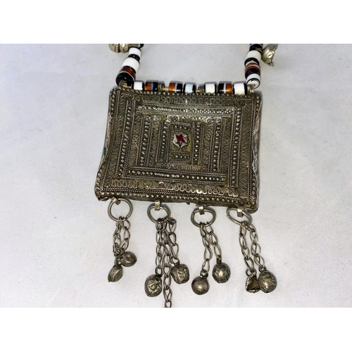 306 - A Mid/Far Eastern white metal large pendant of filigree rectangular form, on variegated bead necklac... 