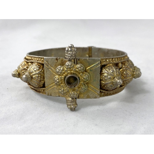 344 - An unusual skull pendant containing miniature dice; a Middle Eastern hinged bangle in ornate white m... 