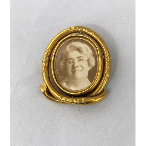 352 - A Victorian gilt metal oval brooch with central swivel double sided photo miniatures