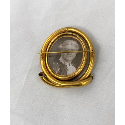 352 - A Victorian gilt metal oval brooch with central swivel double sided photo miniatures