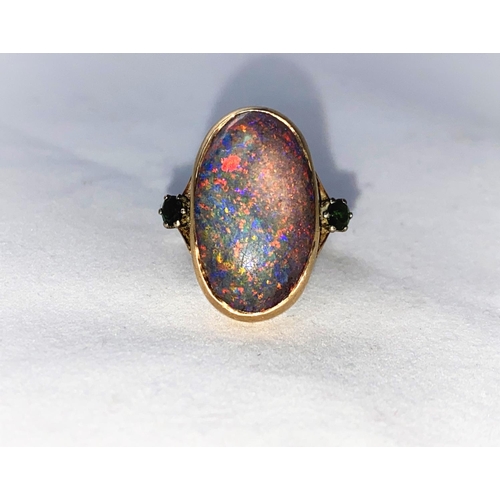 375 - A yellow metal dress ring set large oval black opal coloured stone, flanked by 2 green stones, stamp... 