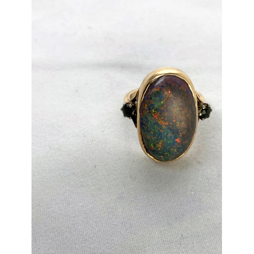 375 - A yellow metal dress ring set large oval black opal coloured stone, flanked by 2 green stones, stamp... 