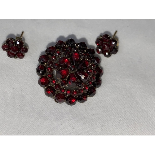 396 - A late Victorian/Edwardian suite of garnet jewellery:  double row bracelet, circular tiered brooch a... 