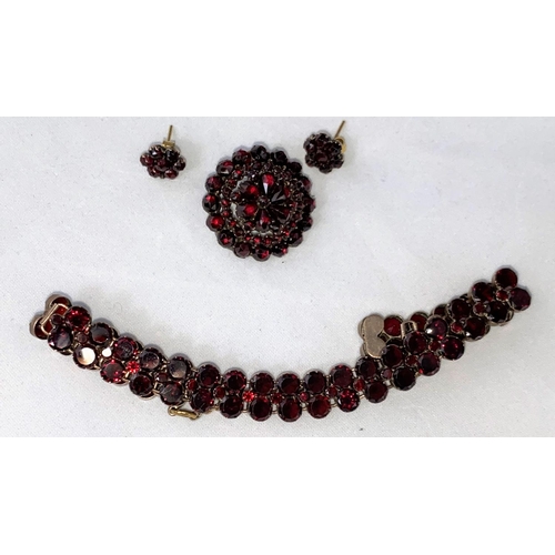 396 - A late Victorian/Edwardian suite of garnet jewellery:  double row bracelet, circular tiered brooch a... 