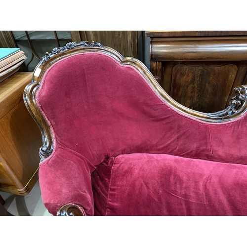 609 - A Victorian rosewood framed chaise longue with foliate carved rails and uprights, on scroll carved s... 