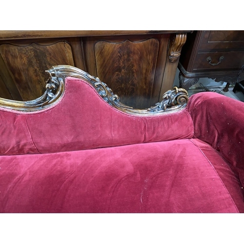 609 - A Victorian rosewood framed chaise longue with foliate carved rails and uprights, on scroll carved s... 