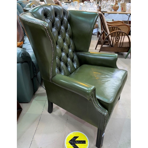 509 - A pair of gentleman's leather wing back armchairs with deep button backs, studded borders in green, ... 