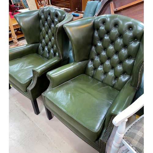 509 - A pair of gentleman's leather wing back armchairs with deep button backs, studded borders in green, ... 