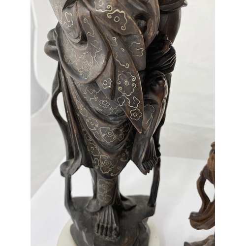 141 - A Chinese wooden carving of a man holding animal on one leg, mounted on marble effect base, inlaid w... 