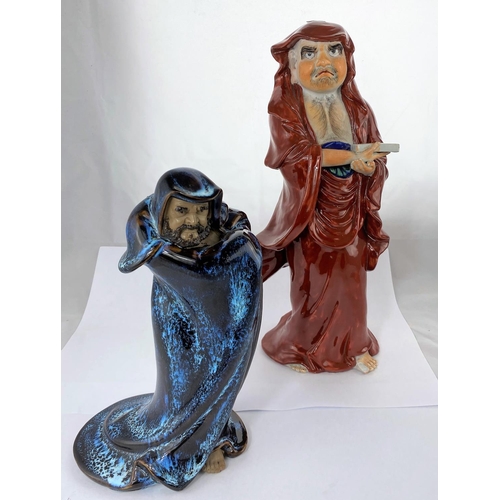 149 - Two Oriental ceramic figures of men in cloaks, one with red glaze, the other mottled blue and brown,... 