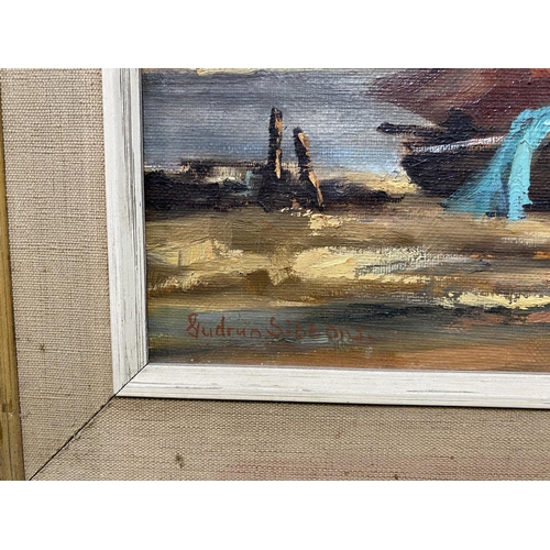 443 - Gudrun Sibbons:  Shoreline scene with beached sailing boats and white cottages, oil on canvas, signe... 