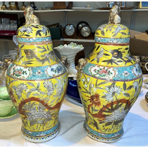 133 - A Chinese pair of baluster covered vases with temple dog finials, mask and ring side handles, decora... 
