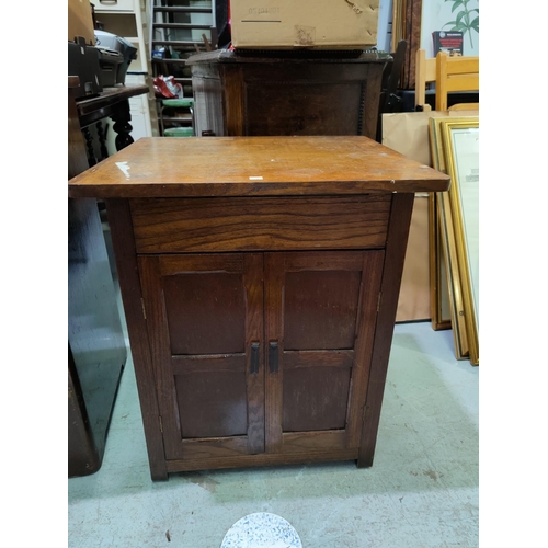 567B - An oak cased Singer treadle sewing machine; a 1930's oak dwarf cabinet enclosed by 2 doors