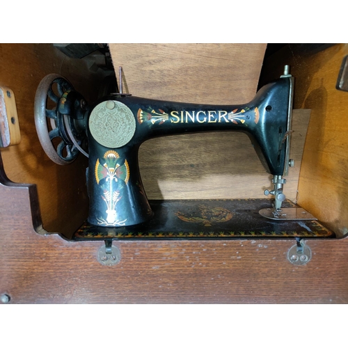 567B - An oak cased Singer treadle sewing machine; a 1930's oak dwarf cabinet enclosed by 2 doors