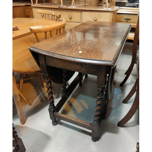 532 - A 1930's oak drop leaf table with oval top on barley twist legs