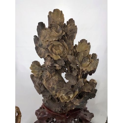147 - A large Chinese soapstone carving of bird in bush in mottled green and brown, attached to red natura... 