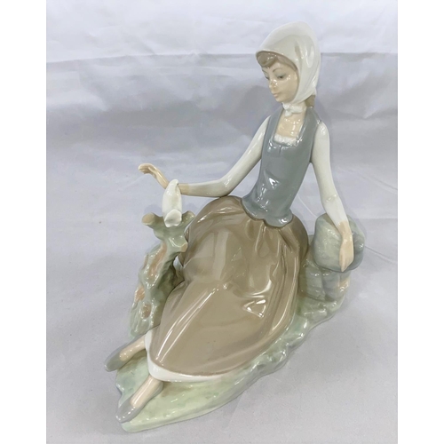 249 - A Lladro group of young woman seated looking at a dove