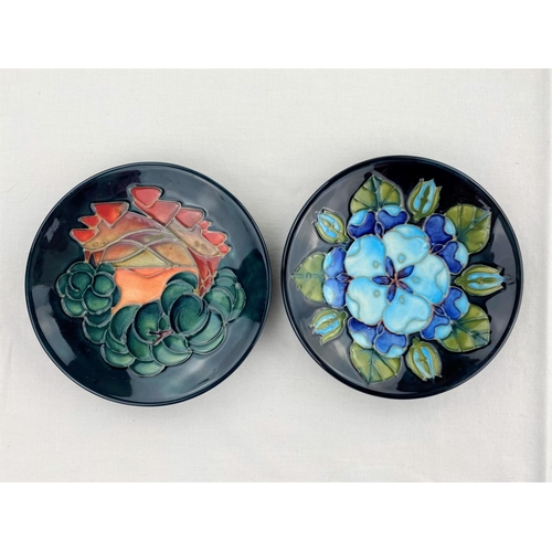 36 - 2 circular Moorcroft pin dishes decorated with blue flowers & leaves, orange flower & fruit respecti... 