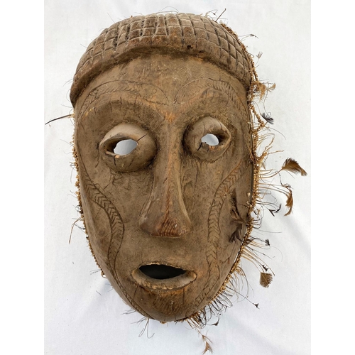 158 - A large African tribal mask, carved snake decoration applied grass and feather border 41cm