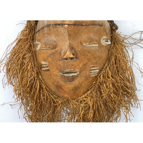 159 - An African tribal mask with applied grass beard, woven grass and fabric head covering, 38cm