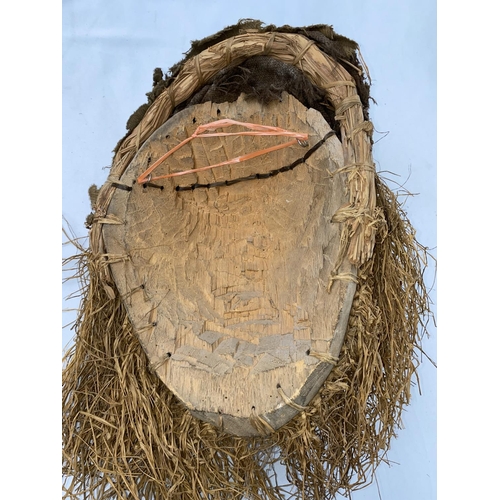 159 - An African tribal mask with applied grass beard, woven grass and fabric head covering, 38cm